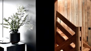 A modern interior with a wooden staircase leading to a loft area, a potted plant, and a minimalist design. - Chalet Enigma – Luxury at the Foot of the Slopes for 17 Guests with Spa (LA CLUSAZ)
