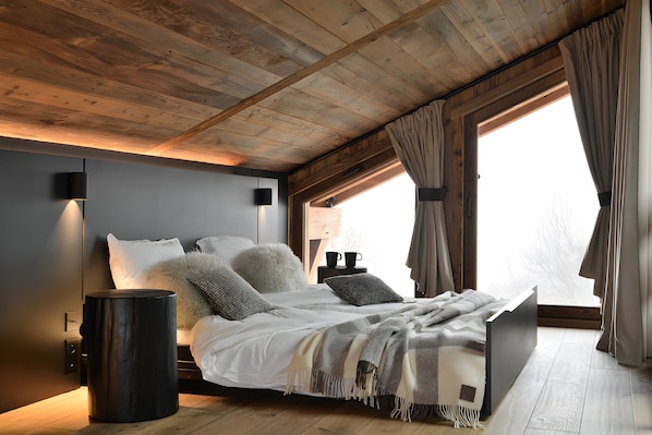 A bedroom with a bed, bedside tables, a lamp, and a window with curtains.