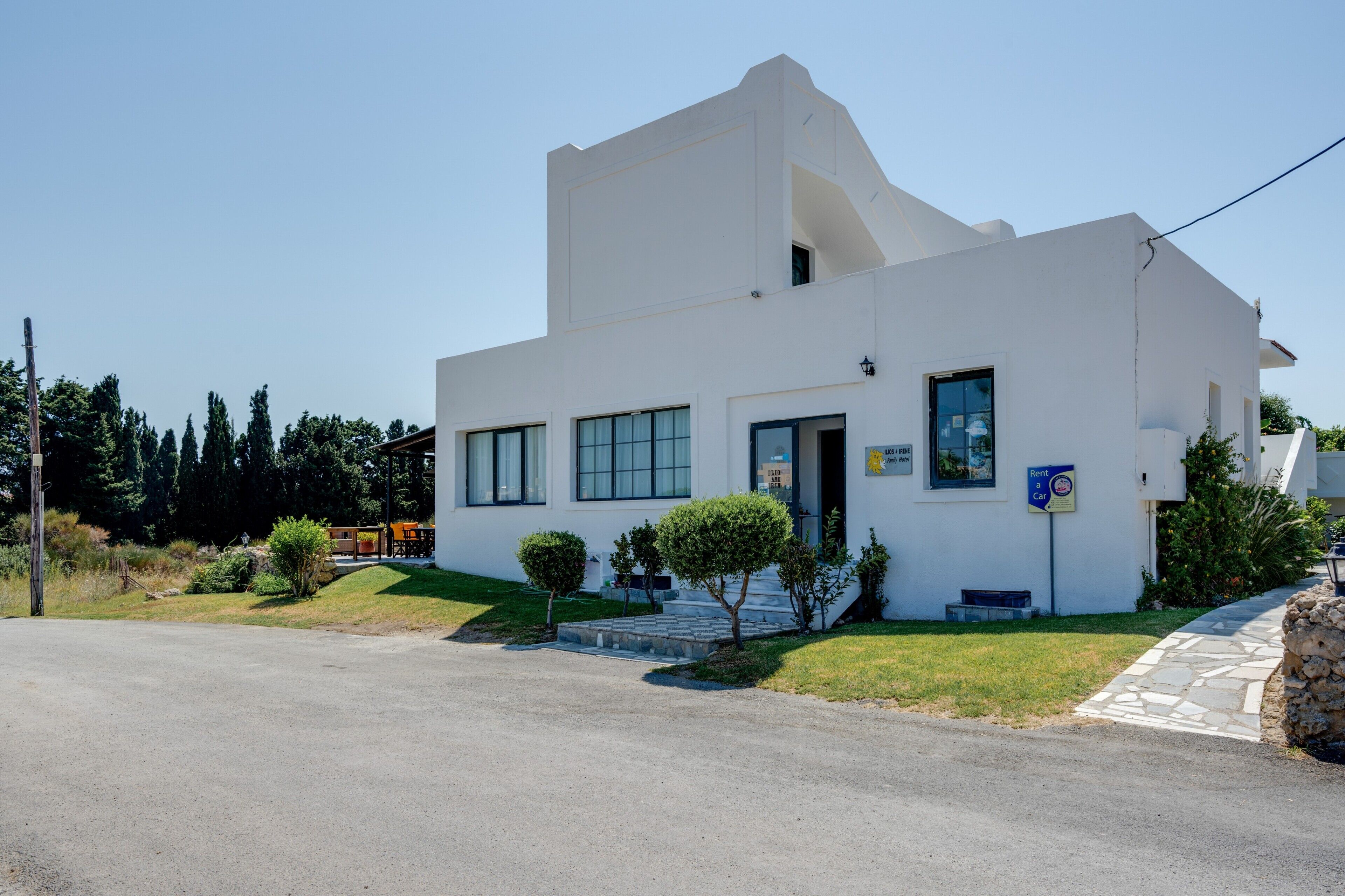 A modern white building with a flat roof, large windows, and a small front porch.