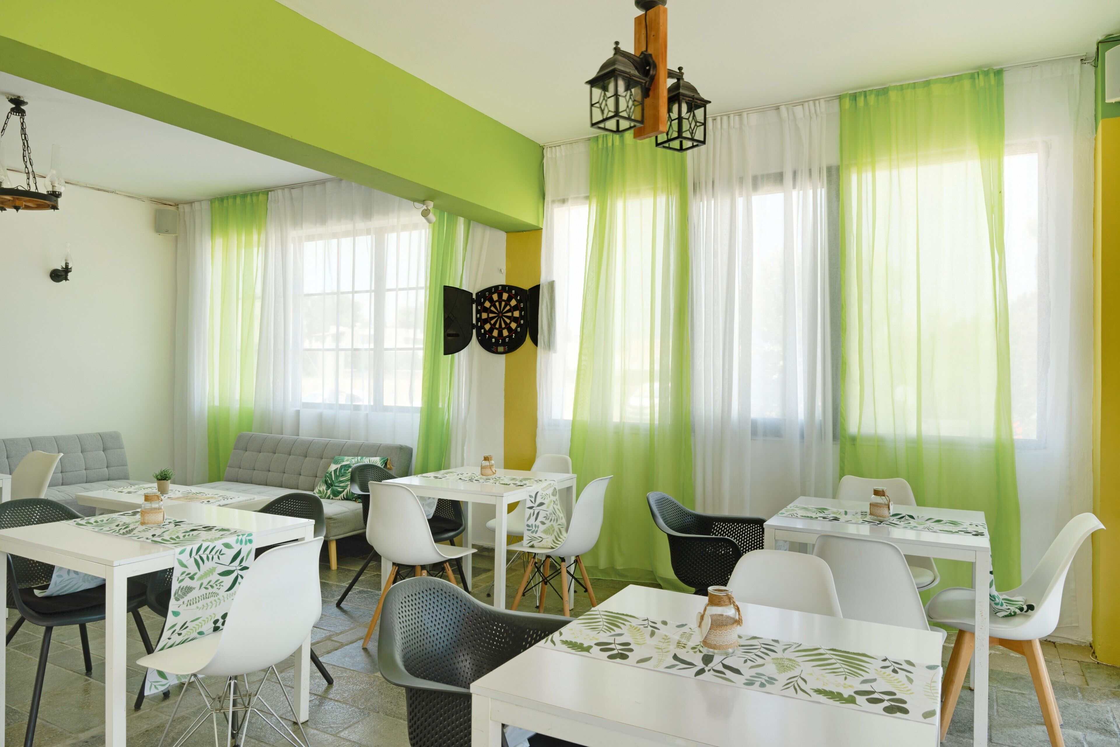 A dining area with tables and chairs, a sofa, and a dartboard.