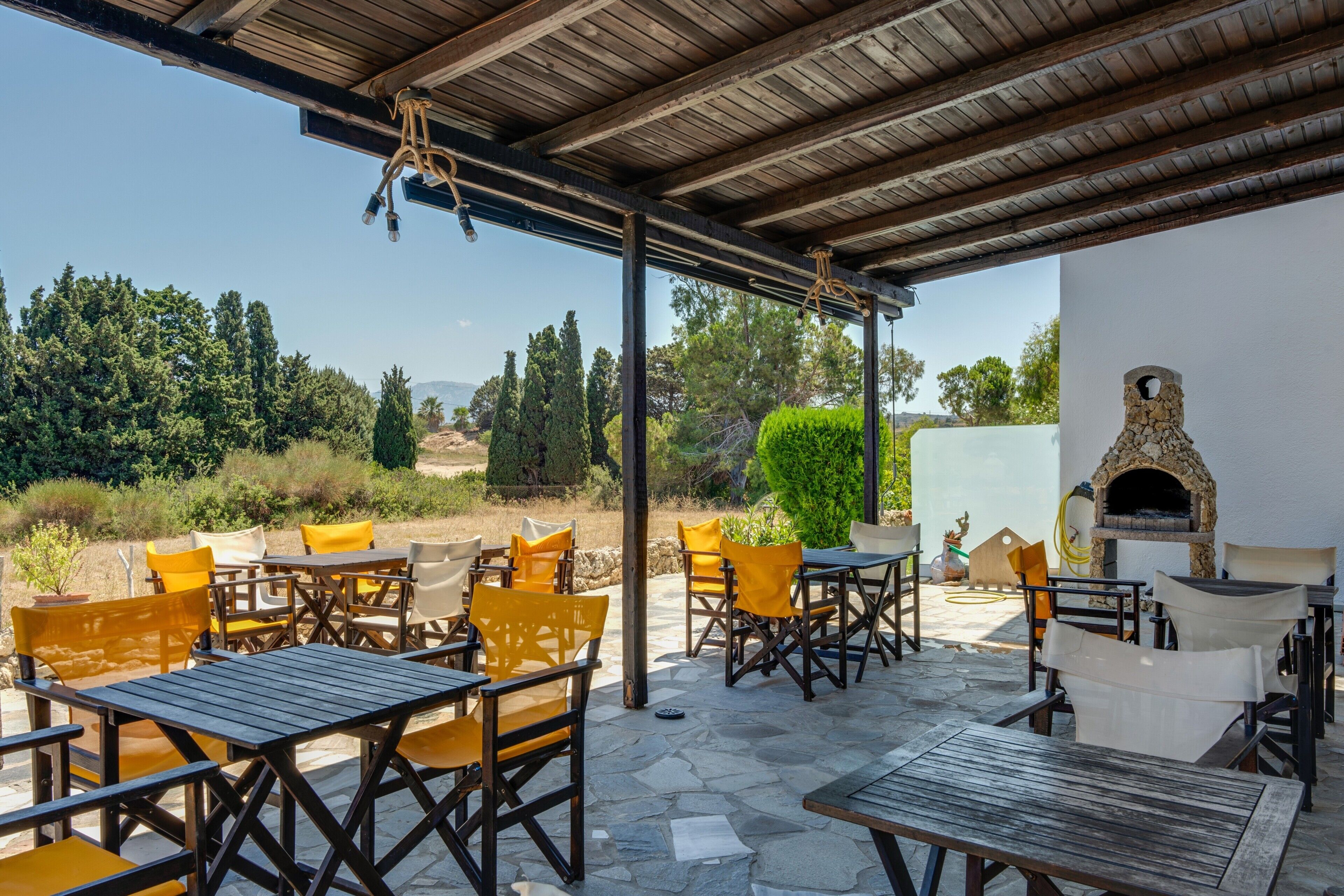 An outdoor patio with tables and chairs, a stone floor, and a stone oven.