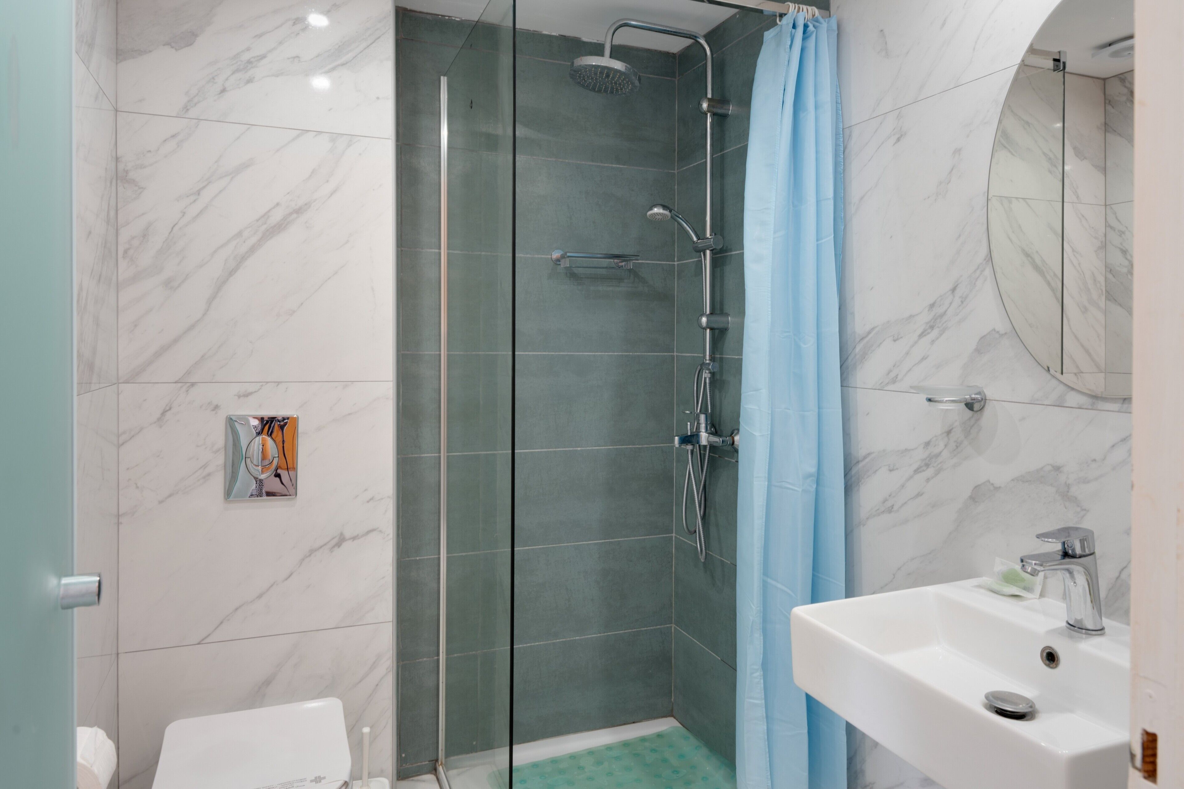 A modern bathroom with a glass-enclosed shower, a white sink, and a toilet.