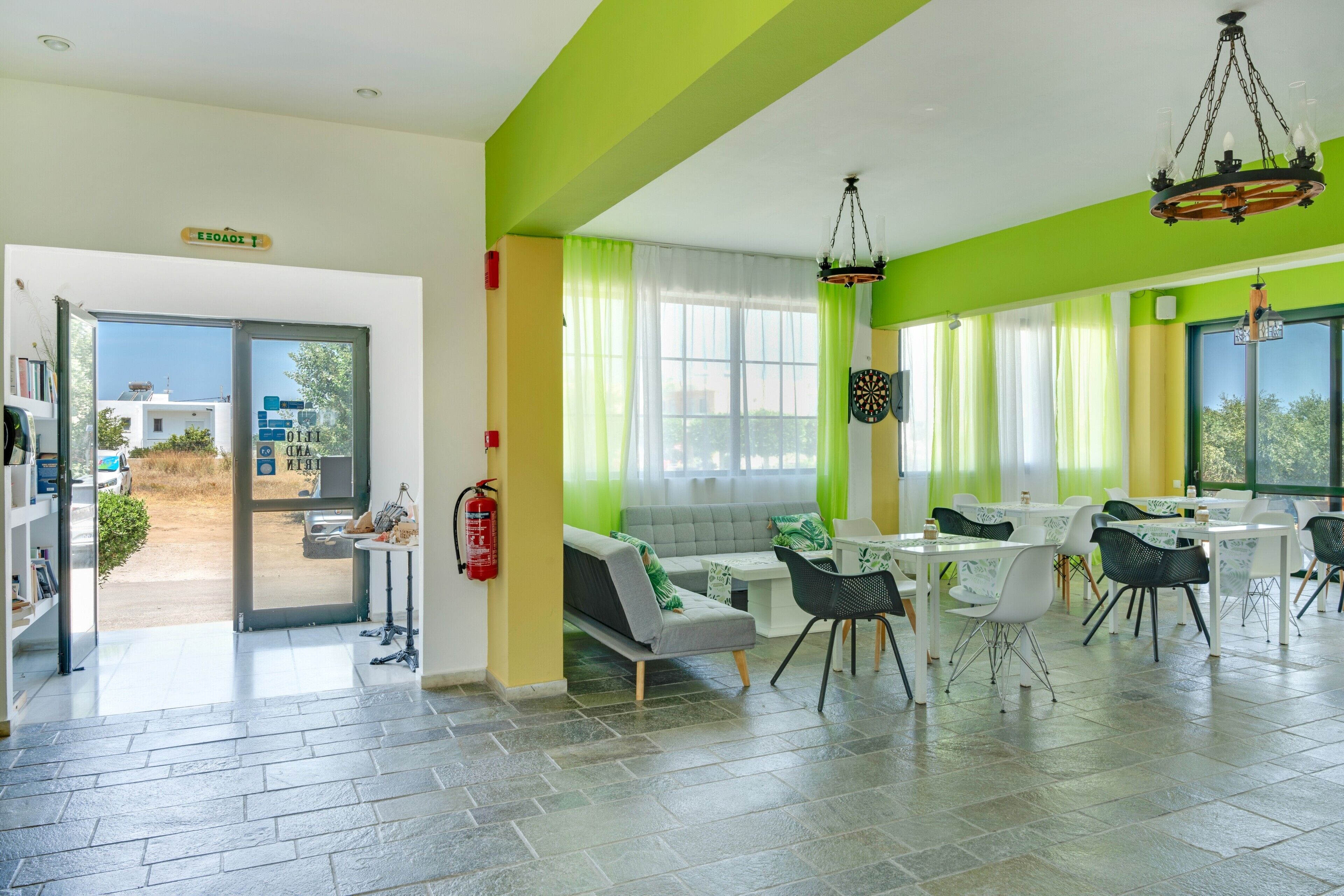 A spacious room with a green accent wall, a sofa, dining tables, and chairs.