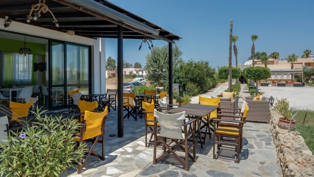 An outdoor patio with stone flooring, yellow and white chairs, and a covered seating area. - Bed and Breakfast 'Ilios and Irene  3' with Shared Terrace, Wi-Fi and Air Conditioning (?ast??a??)