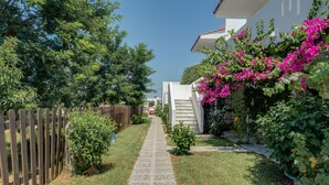 A pathway leading to a house with a wooden fence on one side and flowering plants on the other. - Bed and Breakfast 'Ilios and Irene  6' with Shared Terrace, Wi-Fi and Air Conditioning (?ast??a??)