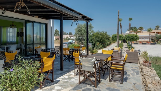 An outdoor patio with stone flooring, yellow and white chairs, and a covered seating area. - Bed and Breakfast 'Ilios and Irene  6' with Shared Terrace, Wi-Fi and Air Conditioning (?ast??a??)