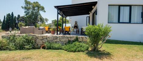 Ein modernes Haus mit Terrasse, Steinmauer und Gartenmöbeln.
