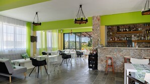 A dining area with tables and chairs, a bar with shelves of bottles, and a stone wall. - Bed and Breakfast 'Ilios and Irene  9' with Shared Terrace, Wi-Fi and Air Conditioning (?ast??a??)