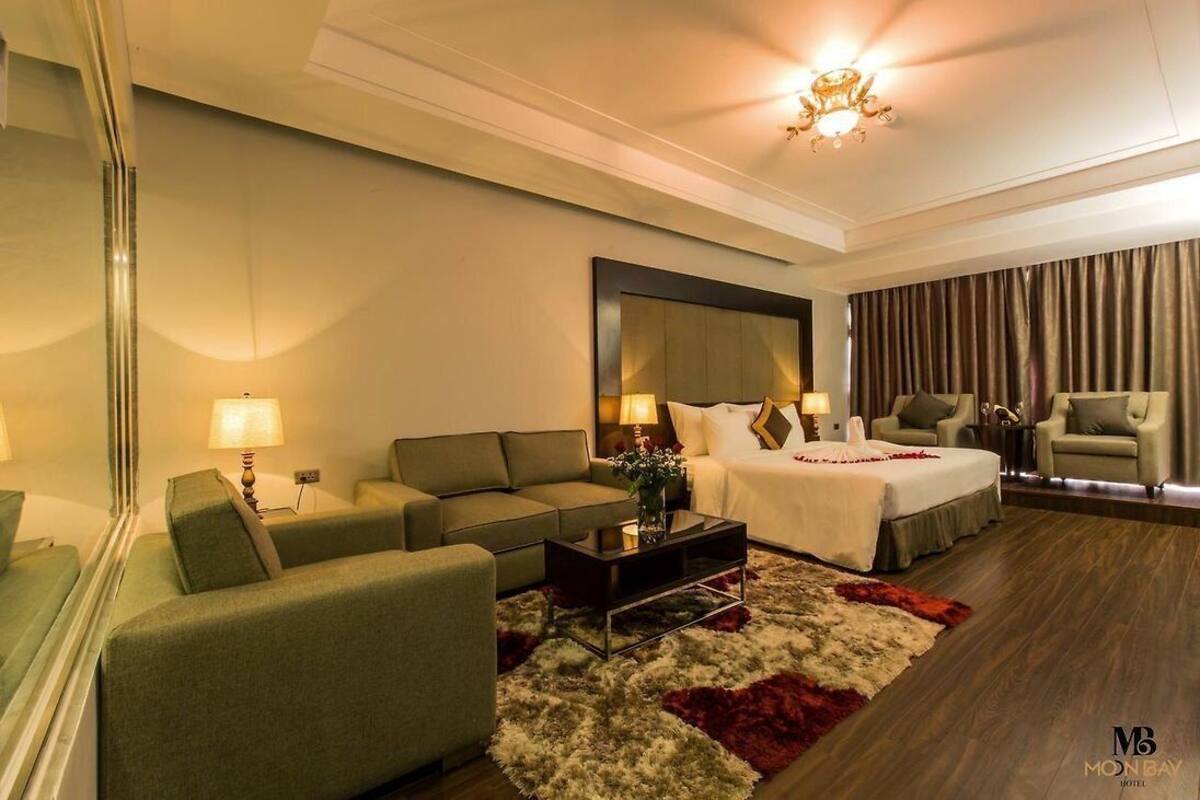 A hotel room with a bed, two sofas, a coffee table, and a large mirror.