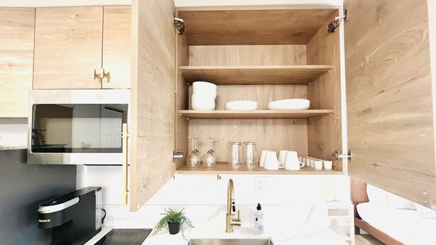 Une cuisine moderne avec des meubles en bois, un évier en acier inoxydable et un four à micro-ondes encastré.