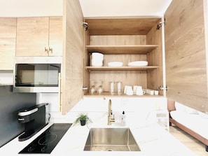 A modern kitchen with wooden cabinets, a stainless steel sink, and a built-in microwave.