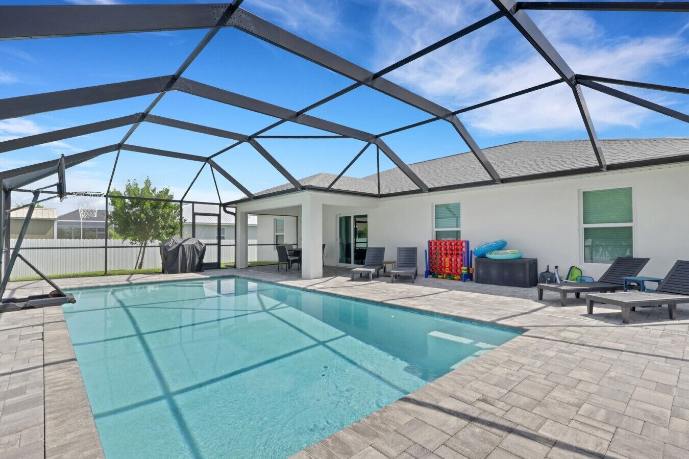 Ein Schwimmbecken mit überdachtem Bereich, Liegestühlen und einer Terrasse.