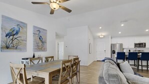 Un amplio espacio habitable con una mesa de comedor, sillas de madera, un sofá gris y un ventilador de techo.