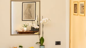 A breakfast table with a vase of white orchids, a laptop, and a framed artwork above it.