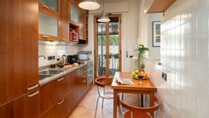 A compact kitchen with wooden cabinets, a double sink, and a dining area with a table and chairs.