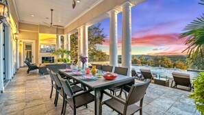 An outdoor patio with a dining table, chairs, and a view of a pool and landscape. - Fortaleza | Hill Country Estate with Infinity Pool, Tennis Court and 3 Acre Grounds (San Antonio)