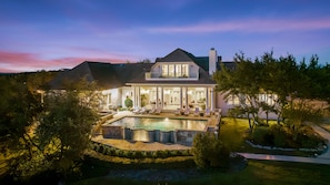 A large house with a swimming pool, a covered patio, and a well-maintained garden.