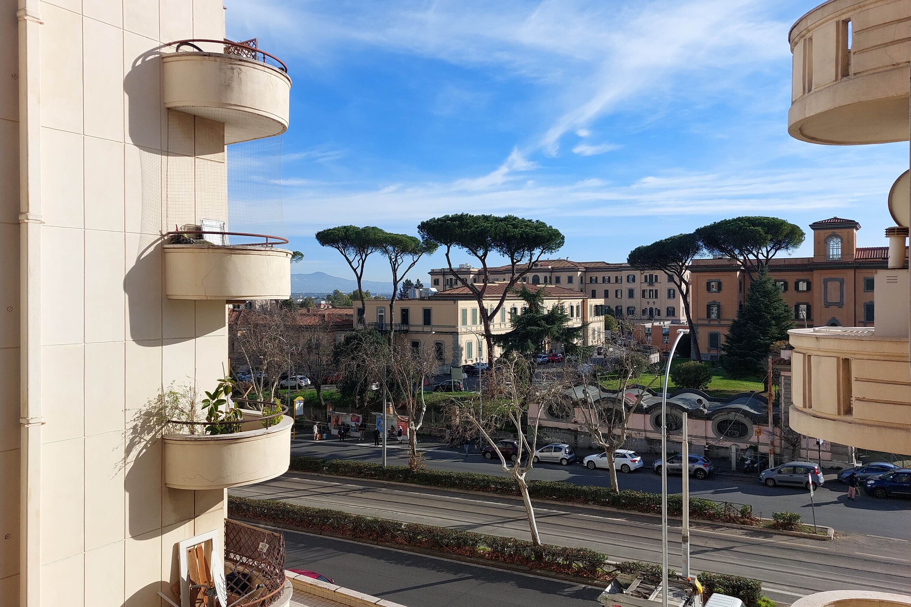 Una vista di una strada con edifici, alberi e auto parcheggiate.