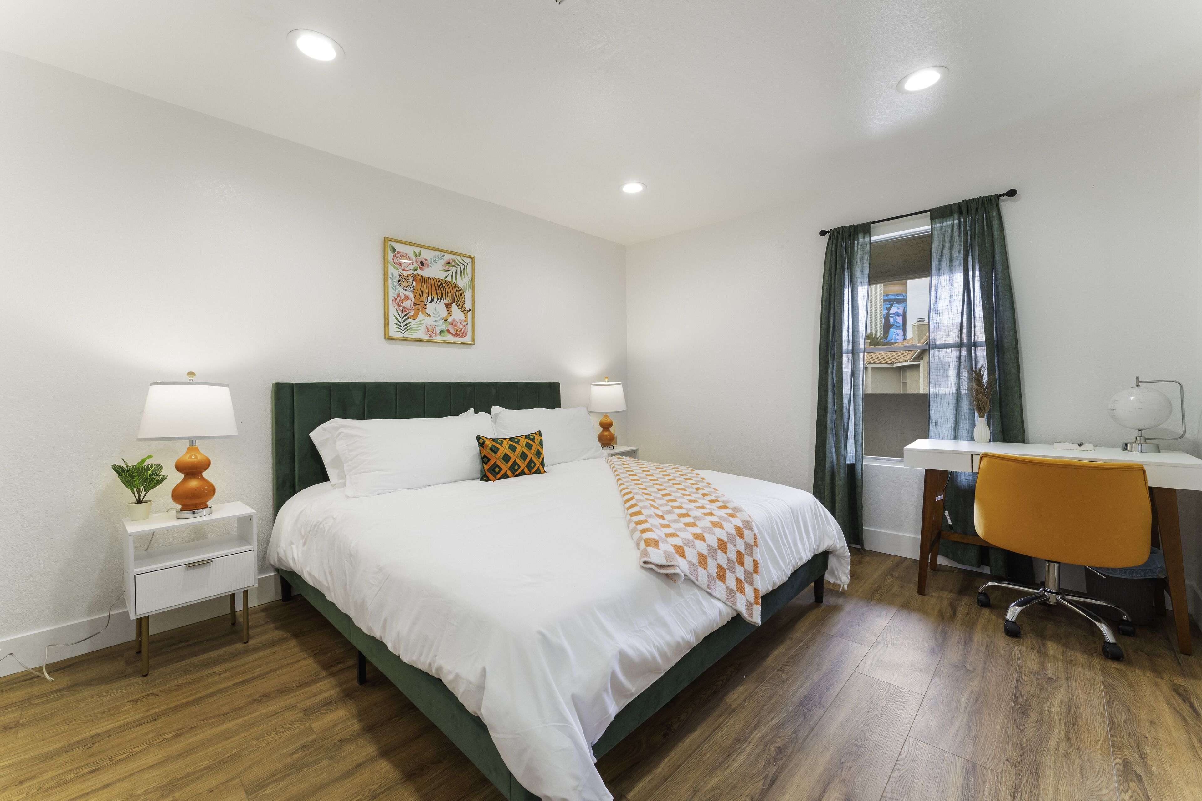 Une chambre à coucher avec un lit, des tables de chevet, un bureau et une chaise.