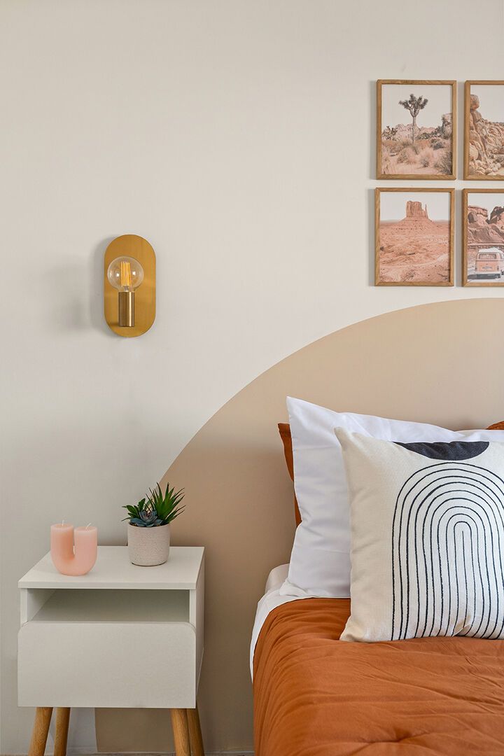 A bedroom with a bed, a bedside table with a lamp, a small plant, and two candles.