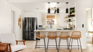 A modern kitchen with a central island, bar stools, and a refrigerator. - Modern Desert Escape - Fire Pit, BBQ and Design (Yucca Valley)
