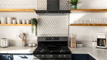 A modern kitchen with a gas stove, a coffee maker, and various kitchen utensils.