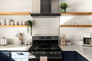 A modern kitchen with a gas stove, a coffee maker, and various kitchen utensils. - Modern Desert Escape - Fire Pit, BBQ and Design (Yucca Valley)