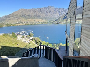 Une vue depuis un balcon donnant sur un lac, avec des bateaux, un port de plaisance et des montagnes en arrière-plan.