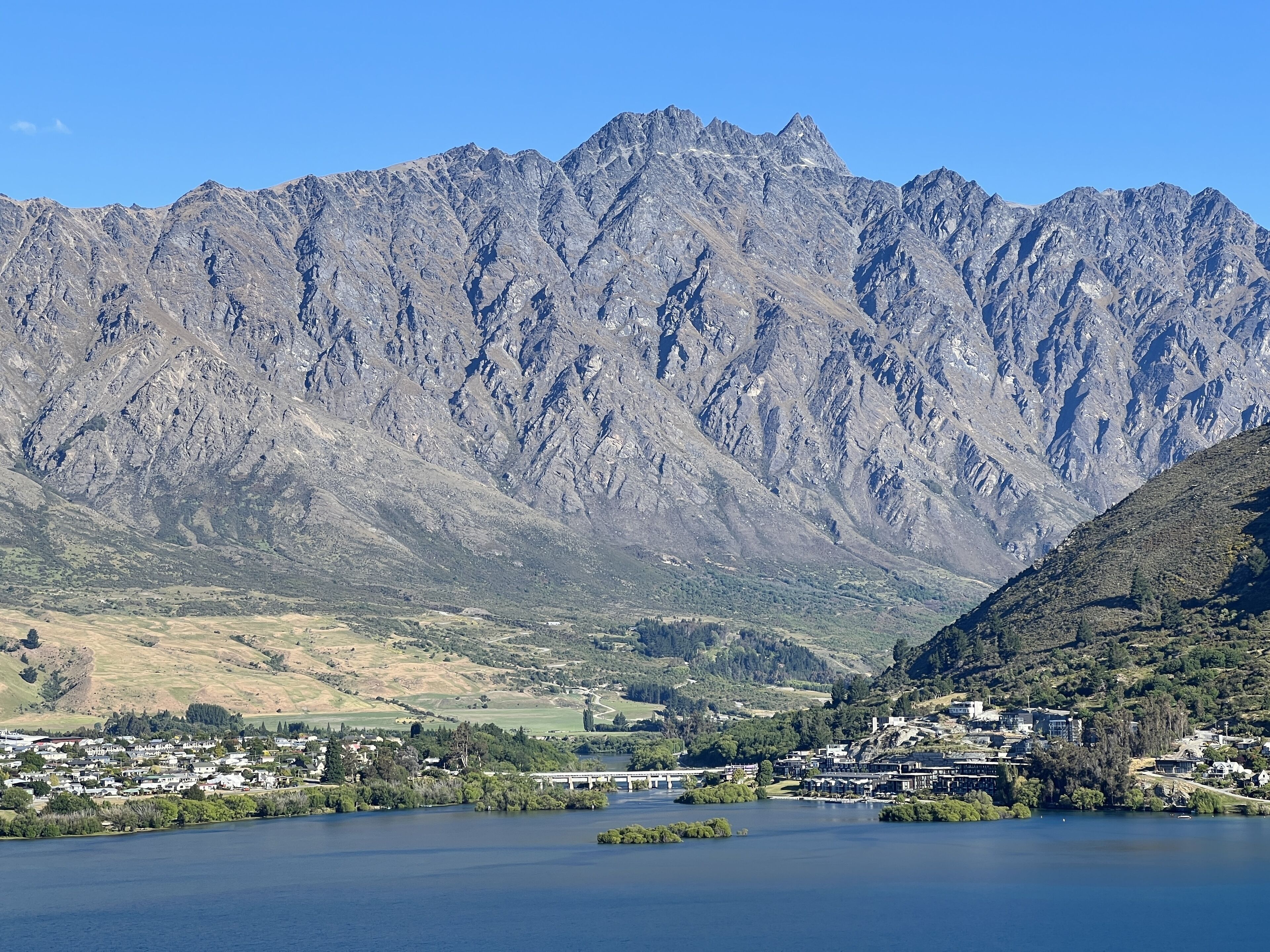 Un paisaje montañoso con un lago y un pueblo pequeño.