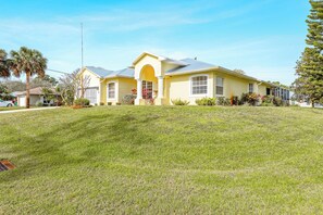Stunning single-story home with arched entrance and covered porch, set amidst a beautifully manicured lawn and lush gardens.