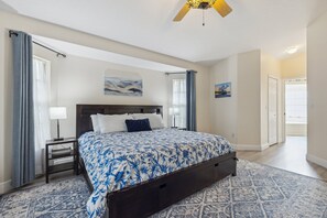 Relax in this serene bedroom with a large bed, nightstand, and ceiling fan.