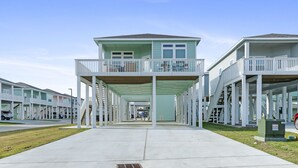 Ein Strandhotel mit einem zentralen Gebäude, das einen Balkon und einen überdachten Zugangsweg besitzt.