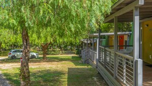 A covered outdoor area with a wooden deck, a car parked nearby, and a tree with hanging branches. - Centro Turistico San Nicola by Interhome (Peschici)