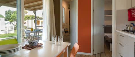 A modern kitchen with a dining area, wooden flooring, and a view of the outside.