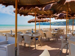 Un restaurant situé en bord de mer, avec une terrasse, des tables et des parasols.