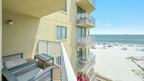 Een balkon met buitenmeubilair, een zwembad en uitzicht op strand en zee.