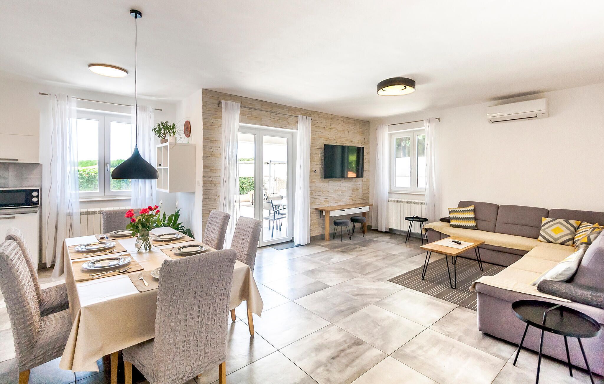 Een moderne woonkamer met een eethoek, een bank en een televisie.