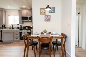 Eine moderne Küche mit Essbereich, ausgestattet mit einem Holztisch, Stühlen und einer hängenden Leuchte.