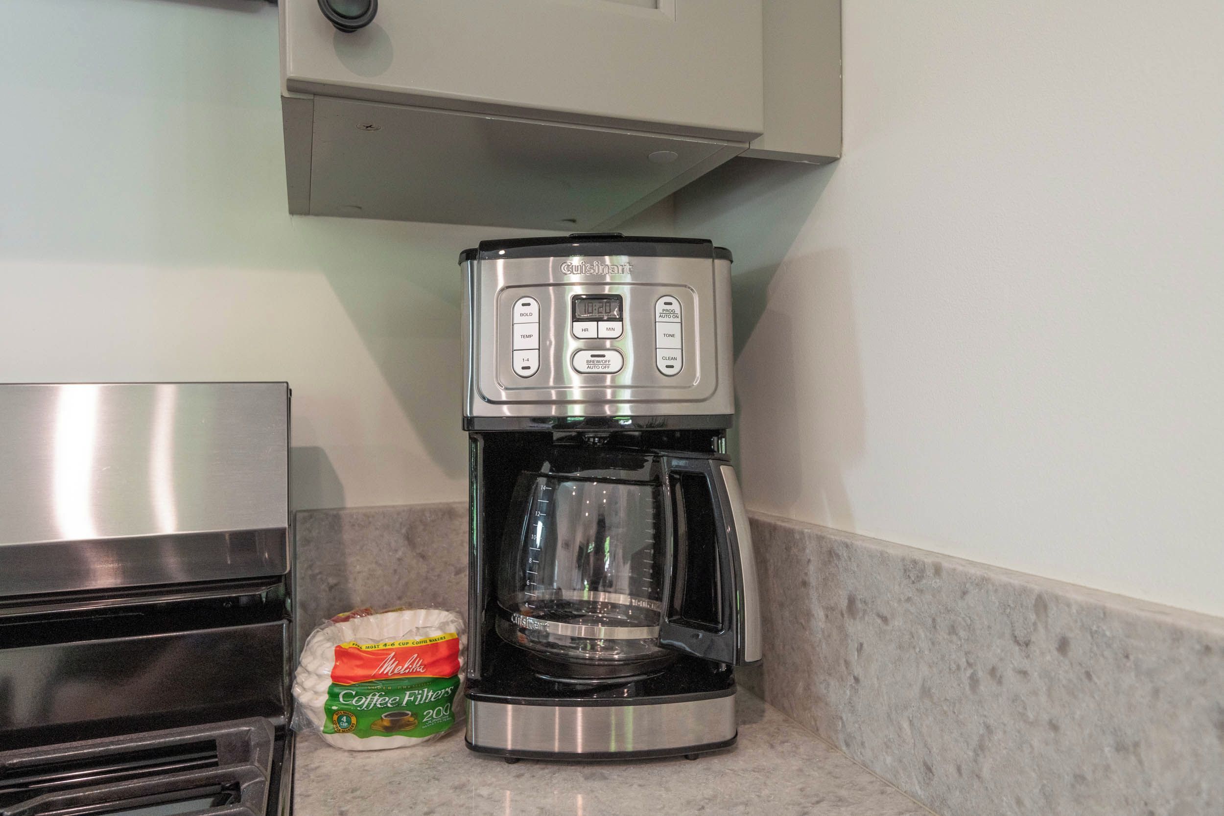 Een keuken met een koffiezetapparaat, een zak koffiefilters en een roestvrijstalen apparaat.