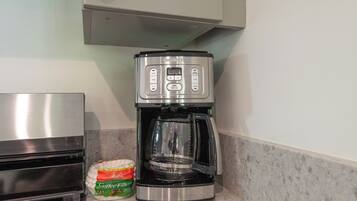 Een keuken met een koffiezetapparaat, een zak koffiefilters en een roestvrijstalen apparaat.