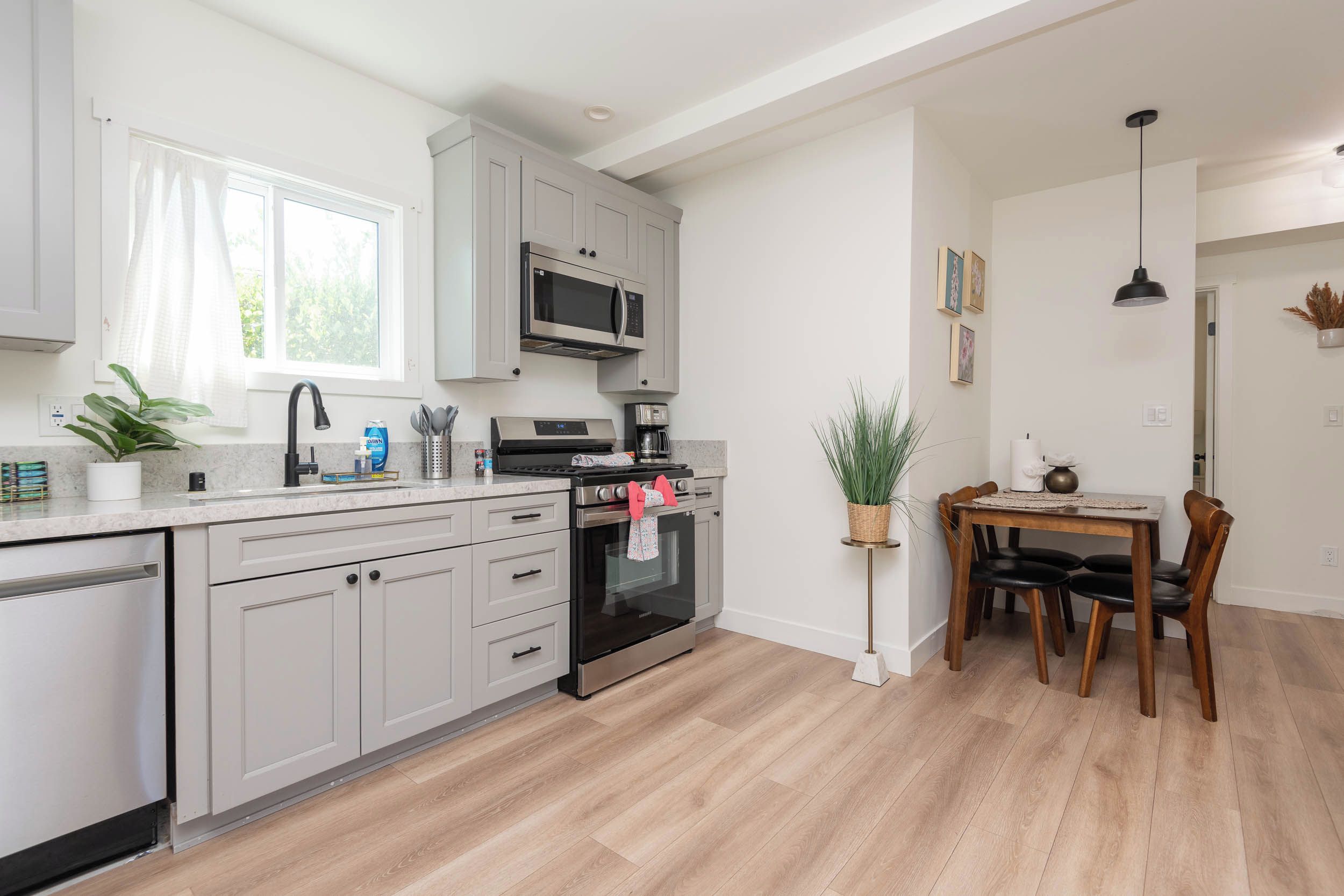 Une cuisine moderne avec des meubles gris, un four à micro-ondes encastré et une cuisinière à gaz.