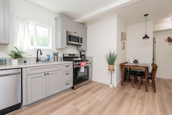 A modern kitchen with grey cabinets, a built-in microwave, and a gas stove.