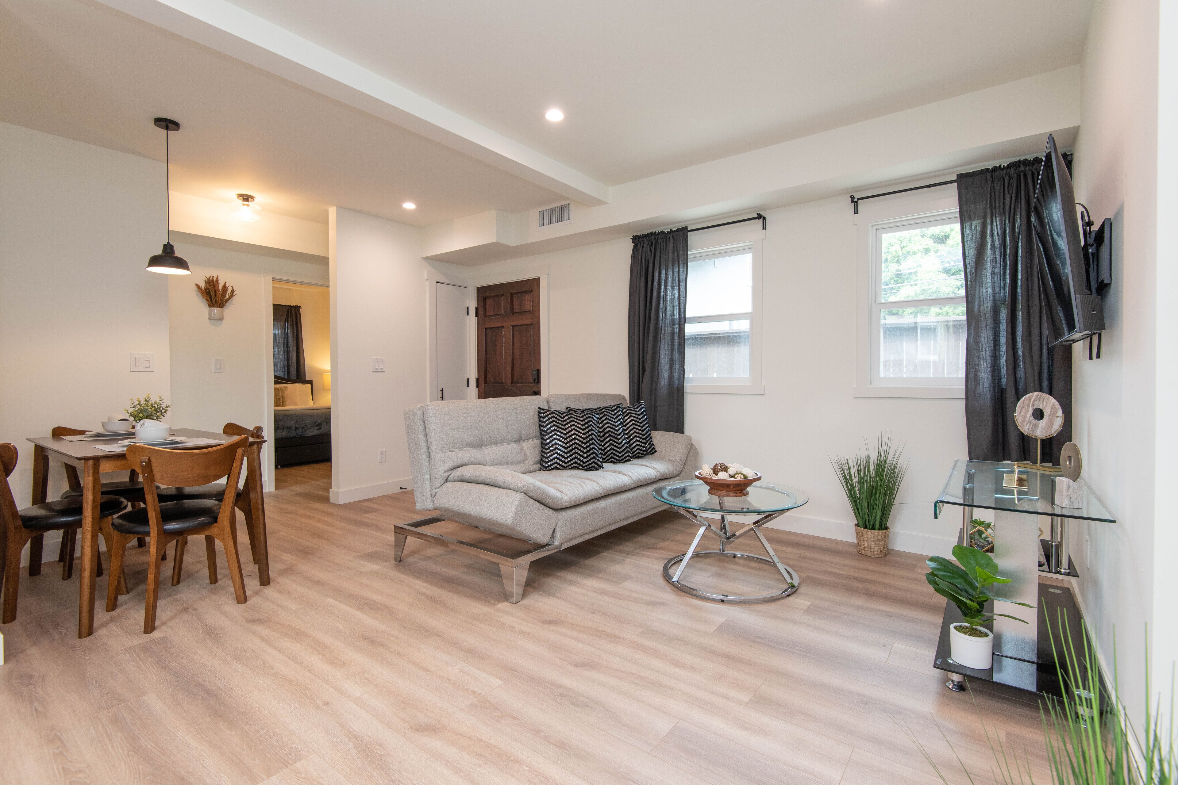 A modern living room with a sofa, coffee table, and dining area.