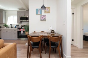 A modern kitchen with grey cabinets, a microwave, and a sink. There is a dining table with chairs and a vase with flowers.