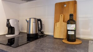 A kitchen with a coffee maker, a kettle, and a bottle of olive oil on the counter. - Ghiberti - Studio in the City Center (Trieste)