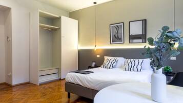 Ein modernes Schlafzimmer mit Bett, Nachttischen, einer Nachttischlampe, einer Topfpflanze und einem Kleiderschrank.