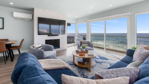 Een moderne woonkamer met een grote televisie, comfortabele zithoek en uitzicht op de oceaan.