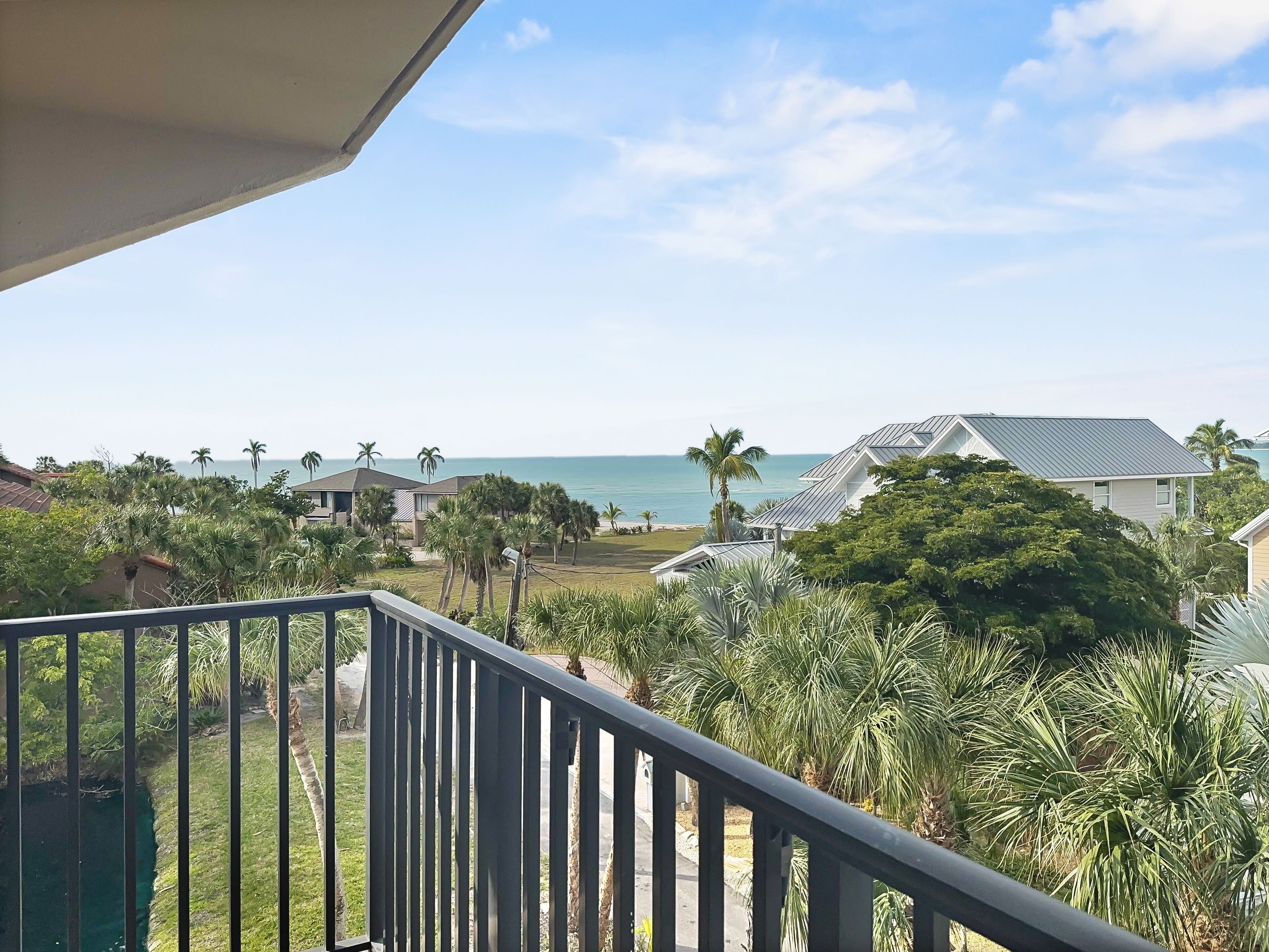 A balcony with a view of the ocean and palm trees.
