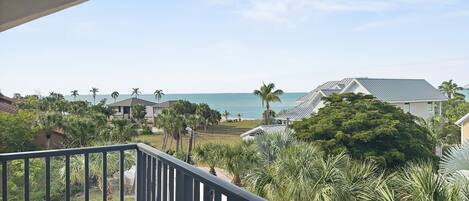 A balcony with a view of the ocean and palm trees.