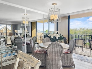 A spacious balcony with wicker furniture and a glass table, overlooking a scenic view.